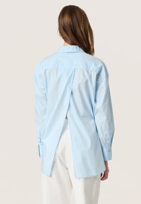 Cămașă bleu deschis, din bumbac, cu mâneci lungi, slit pe spate și guler clasic. Design simplu, textură ușoară.
