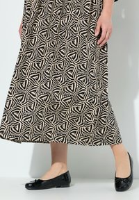Černá a béžová sukně se vzorem a geometrickým designem, doplněná černými lakovanými balerínami s mašlí a krokodýlovou texturou.