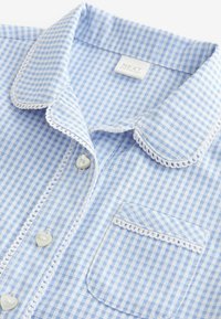 Lichtblauw en witte gingham geblokte shirt met een gegolfde kraag, hartvormige knopen en een patch pocket met kantafwerking.