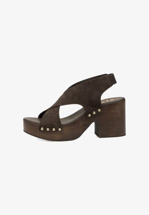 Sandalia de plataforma de ante marrón con tacón de bloque de madera, tiras cruzadas, tachuelas doradas y correa trasera elástica.