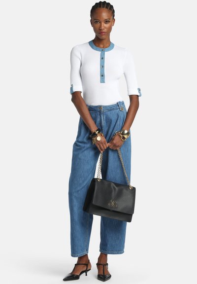 Haut blanc côtelé avec détails en denim, jean bleu taille haute, sac à main noir avec ferrures dorées, et chaussures noires pointues.