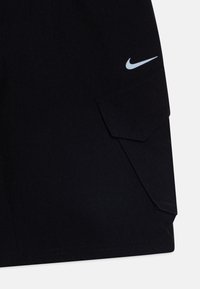 Sorte shorts med teksturert stoff, med en frontlomme med klaff og en lyseblå Nike-logo på siden.