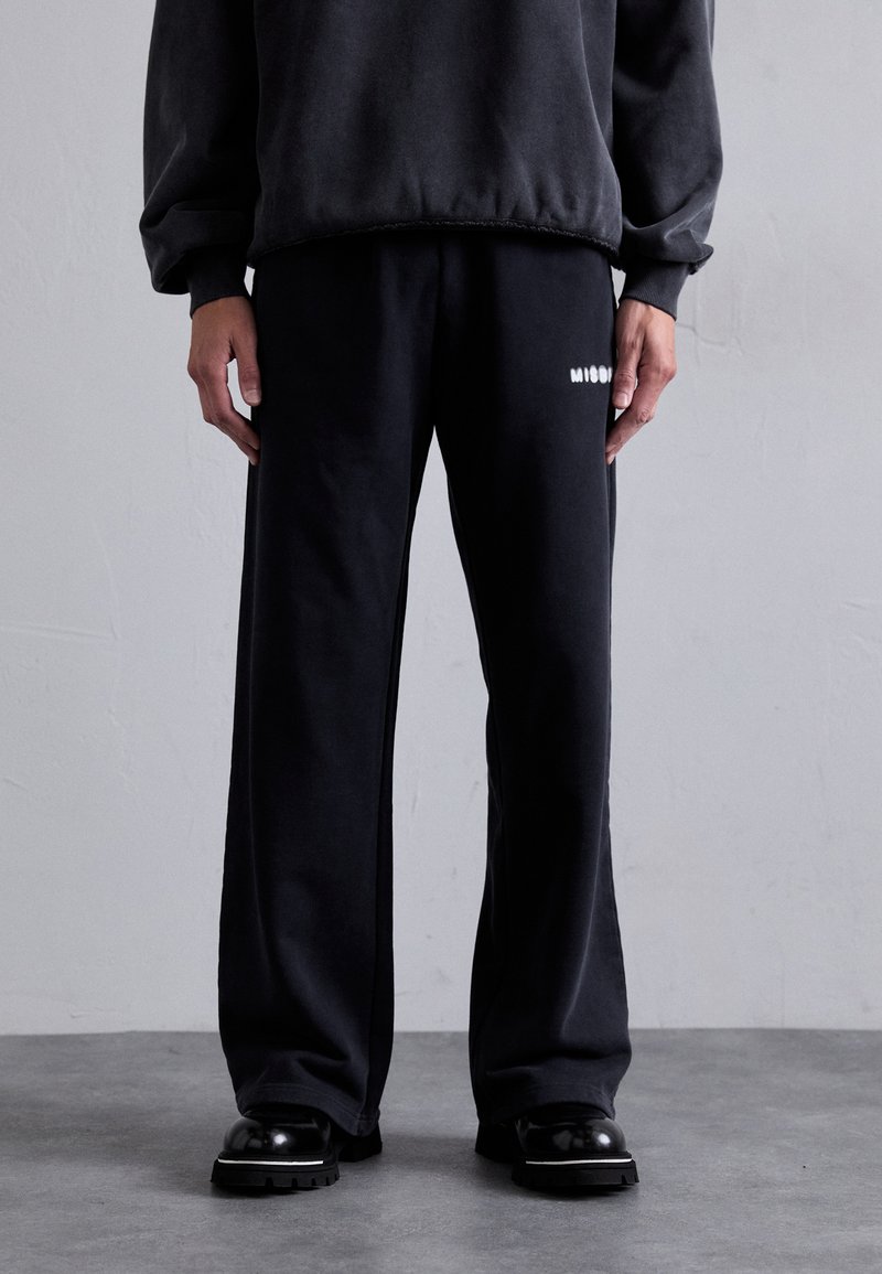 Sorte joggingbukser lavet af blødt materiale, med en afslappet pasform og hvidt logo. Parret med en matchende, mørk oversized sweatshirt.