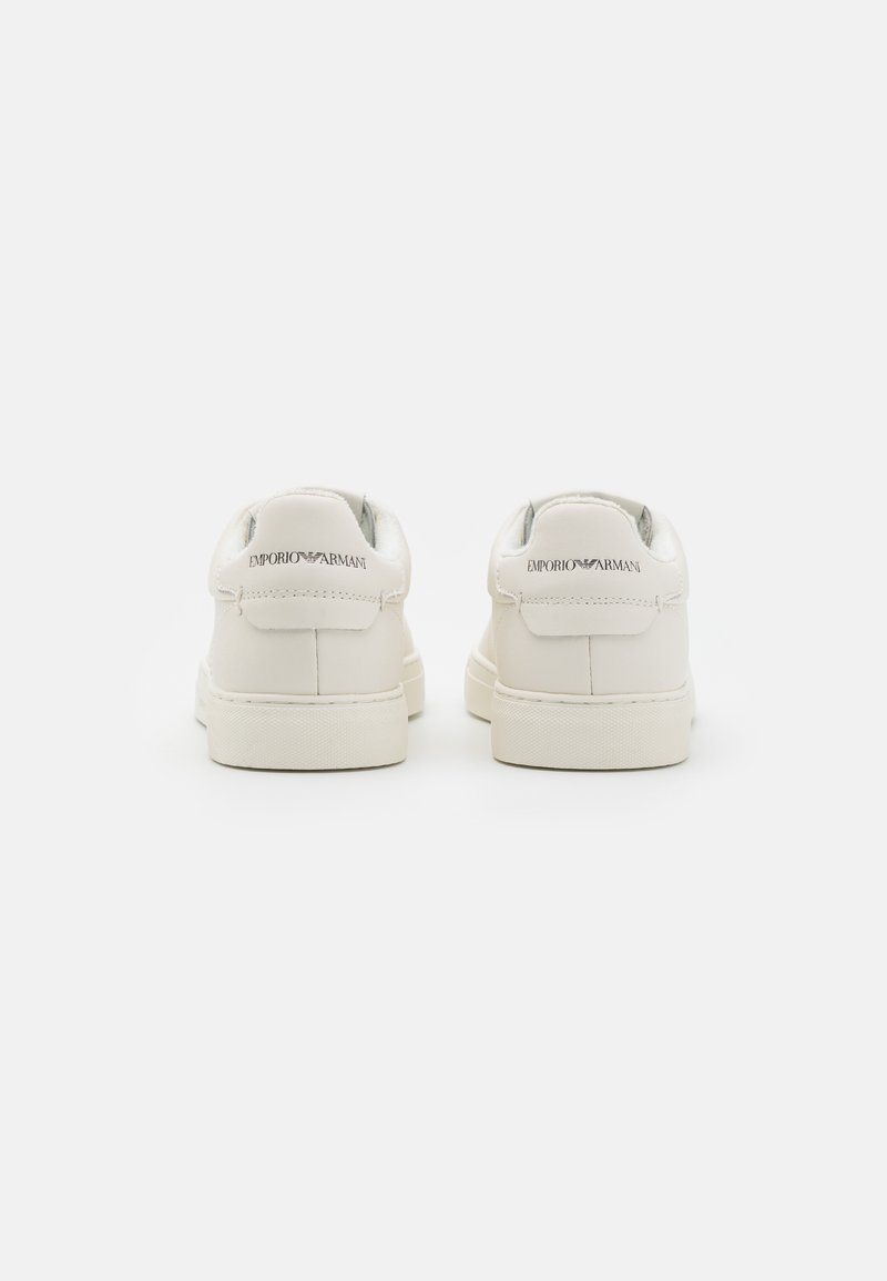 Baskets en cuir blanc avec une finition lisse, orteils ronds, cols rembourrés et semelles en caoutchouc contrastées ; caractéristiques logo embossé au niveau des talons.