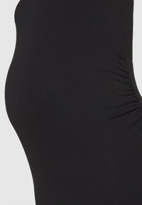 O vestido de maternidade preto apresenta um tecido suave, um design ajustado ao corpo e detalhes franzidos na lateral para um ajuste confortável.