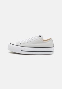 Graue Leinenschuhe mit weißen Schnürsenkeln, Gummi-Zehenkappe und erhabenem Sohle mit schwarzem Streifenverlauf entlang der unteren Kante.