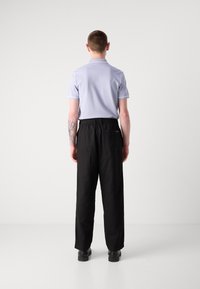 Light purple polo shirt with a collar, short sleeves, and white accents paired with black loose-fitting trousers. Simple, clean design.