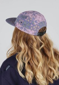Casquette violette et bleue avec un design à motif comportant des formes florales et abstraites ; bandeau ajustable et tissu texturé.