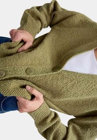 Zelený texturovaný kardigan s žebrovanými rukávy a třemi velkými knoflíky. Materiál vypadá měkce a útulně, s mírně volným střihem.