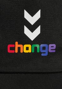 Svart tygkeps med en vit chevron-grafik ovanför ordet "change" i regnbågens färger, som framhäver de livliga bokstäverna mot en texturerad bakgrund.