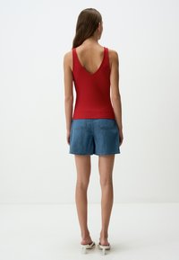 Top rosso a coste con schiena a V, abbinato a pantaloncini in denim azzurro chiaro. I sandali hanno un tacco a blocco. Design semplice e aderente.