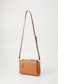 Sac bandoulière en simili cuir brun avec une finition texturée, un compartiment principal zippé et une poche zippée supplémentaire à l'avant. Bandoulière ajustable.