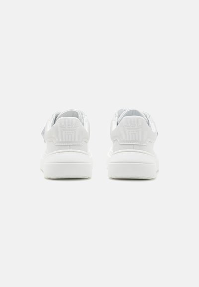 Hvite sneakers med glatt overflate, avrundet tå og tykk såle. Har en subtil preget logo på baksiden og teksturerte hælakkenter.