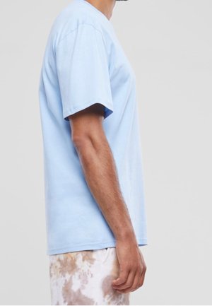 T-shirt en coton bleu clair à manches courtes et col rond, présentant une coupe décontractée. Agrémenté d'une texture subtile et d'un design sans coutures.