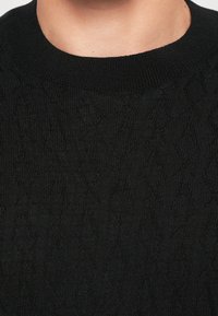 Schwarzer Strickpullover mit einem strukturierten Diamantmuster, rippgestricktem Rundhalsausschnitt und glatter Oberfläche.