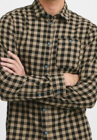 Hnědá a černá kostkovaná flanelová košile s modrými knoflíky, náprsní kapsou a dlouhými rukávy. Měkká textura, střih s normálním volným střihem.