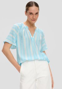 Blouse à manches courtes bleu clair avec des rayures blanches verticales, décolleté en V et coupe décontractée. Fabriquée en tissu léger, avec des détails au niveau du décolleté.