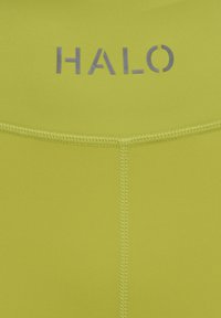 Gulgrønt stof med lodret og vandret syning samt ordet "HALO" trykt i gråt nær øverste centrum.