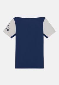 Mornarska polo majica s bijelim ovratnikom i svijetlosivim rukavima. Sadrži tekstualni print na jednom rukavu i teksturiranu tkaninu. Klasičan kroj.