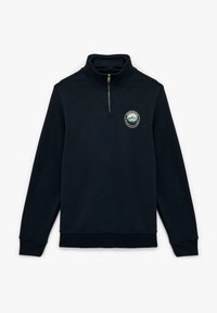 Granatowy sweter z półzamkiem, wykonany z miękkiego materiału, z okrągłą naszywką z motywem górskim na klatce piersiowej oraz prążkowanymi mankietami i dolnym ściegiem.
