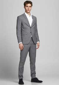 Grauer maßgeschneiderter Anzug mit passender Hose, Blazer mit zwei Knöpfen, Reverskragen und weißem Hemd; schlankes Design mit subtiler Textur.