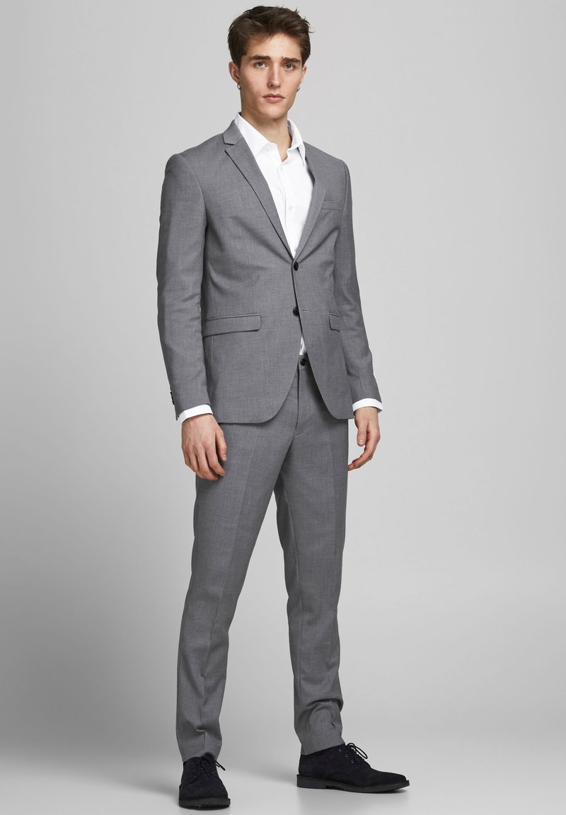 Grauer maßgeschneiderter Anzug mit passender Hose, Blazer mit zwei Knöpfen, Reverskragen und weißem Hemd; schlankes Design mit subtiler Textur.