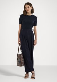 Άνοιχτο μπλε πλεκτό μπλουζάκι κοντό μανίκι σε συνδυασμό με ψηλόμεσες φαρδιές παν trousers, διακοσμημένο με μια ζώνη και μια τσαντάκι με σχέδιο. Μαύρες σανδάλια με λουράκια.