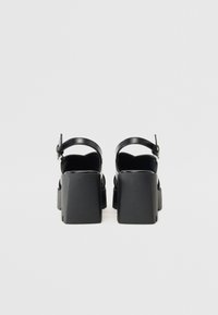 Svart plattform sandaler med blokk hæl, med en bakre ankelrem og glatt lærtekstur. Minimalistisk design og rene linjer.