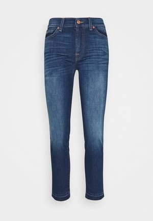 Jean slim fit en denim bleu foncé avec des détails délavés, fermeture à boutons sur l'avant et design à cinq poches, présenté sur un fond clair uni.