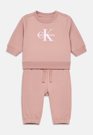 Lichtroze sweatshirt en broek set, gemaakt van zacht katoen, met "Calvin Klein" logo, ronde halslijn, lange mouwen en elastische manchetten.