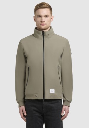 Giacca bomber khaki con colletto a listino, zip frontale completa, polsini elastici, due tasche laterali e una toppa con logo sull'orlo inferiore.