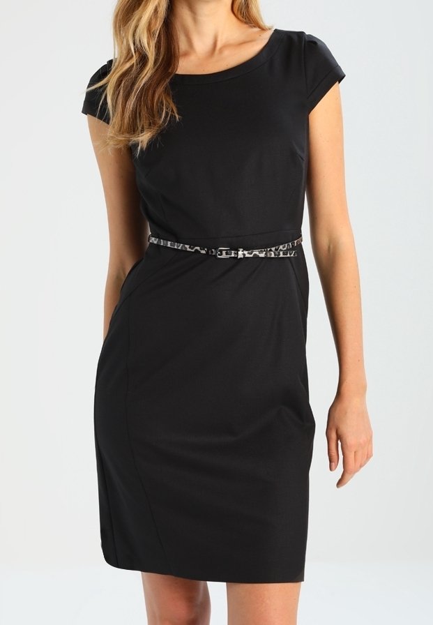 Femme portant une robe noire ajustée longueur genou avec des manches courtes et une fine ceinture à motif animalier à la taille.
