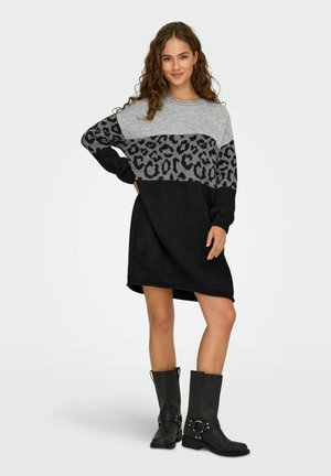 Robe en tricot grise et noire, avec un motif léopard, à manches longues et à coupe décontractée, associée à des bottes noires jusqu'au genou.
