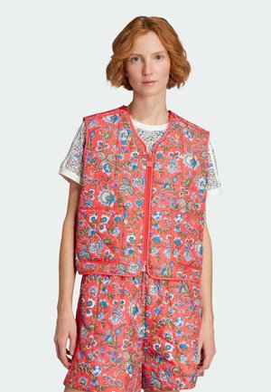 Vatteret vest i klar koral farve med blomster mønstre i blå og grøn, med lynlås lukning og forlommer, lagd over en mønstret skjorte.