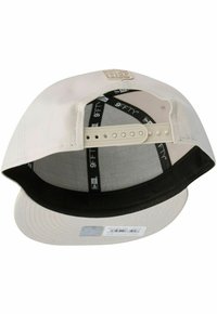 Casquette beige clair avec une doublure intérieure noire, visière courbée et sangle en plastique ajustable. Comprend l'étiquette "9FIFTY" à l'intérieur.
