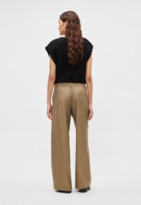 Czarna bluzka z krótkim rękawem i beżowe spodnie z szerokimi nogawkami, prezentujące teksturowane wykończenie i dopasowany krój, z detalem tylnej kieszeni.