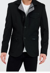 Czarna marynarka o fakturze przypominającej denim, z dwoma kieszeniami na zamek i kontrastującym kołnierzem w paski. Posiada trzy guziki oraz kieszeń na piersi.