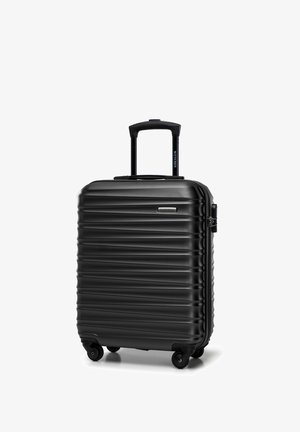Valise rigide noire avec texture à rainures verticales, poignée rétractable et quatre roues pour la mobilité. Dispose d'une fermeture à zip robuste.