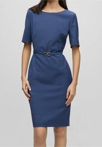 Robe bleu marine avec un motif texturé, manches courtes, coupe ajustée et ceinture à la taille avec un détail de boucle en métal doré.