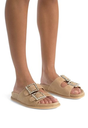 Beige Wildleder Slipper-Sandalen mit zwei großen Schnallen und klaren Strass-Akzenten. Weiche, flache Sohle und offenes Design für zusätzlichen Komfort.