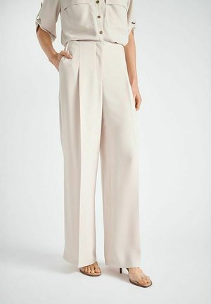 Pantalon à jambes larges en tissu beige clair, avec plis devant, taille haute et poches latérales. Texture lisse avec une légère brillance.