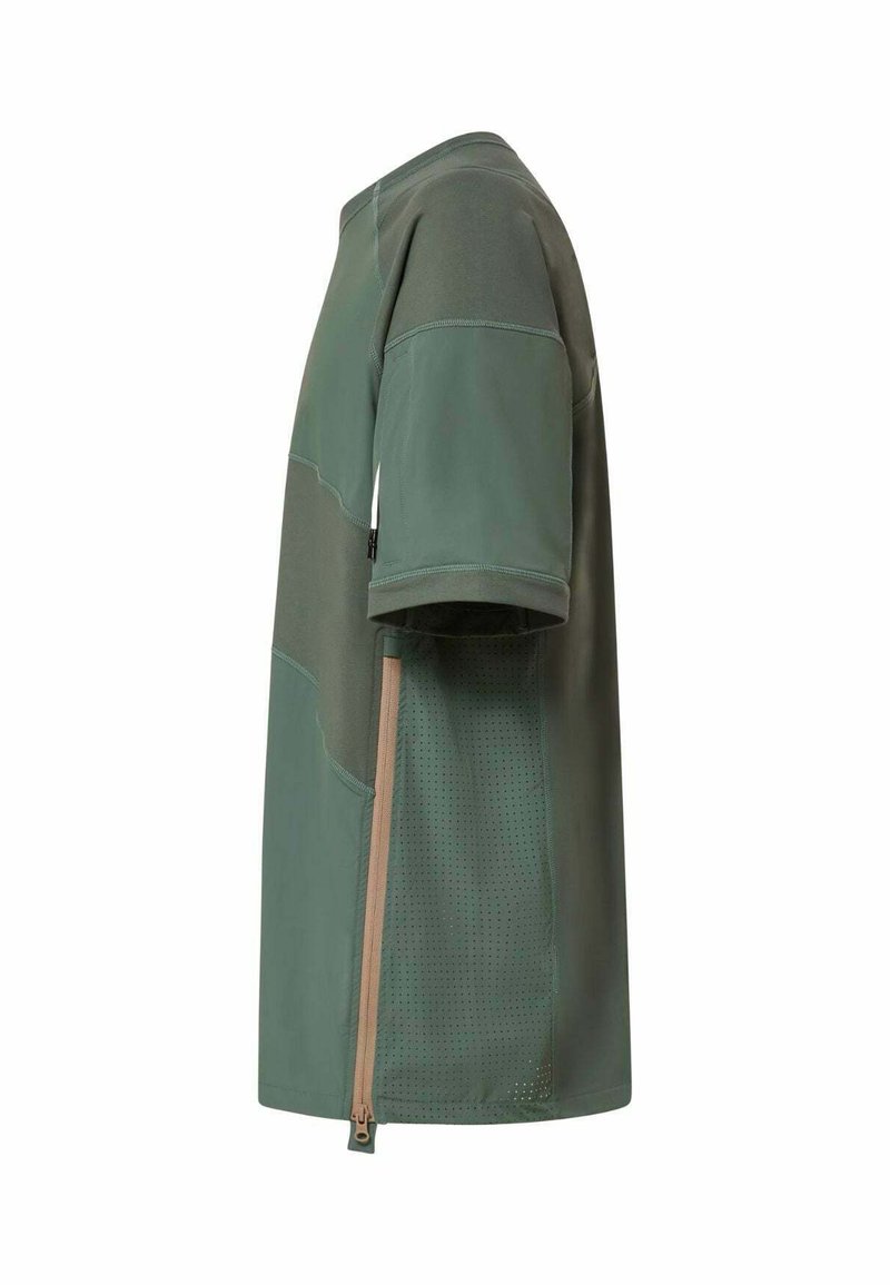 Chemise verte à manches courtes avec des panneaux vert plus foncé, fermeture éclair verticale beige et tissu perforé sur le côté pour la ventilation.