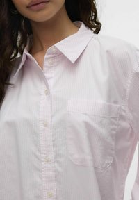 Camisa de botones de rayas rosa claro en algodón con cuello, que presenta un bolsillo en el lado izquierdo del pecho y botones perlados en la parte frontal.