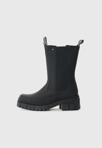 Bottes noires à cheville avec une finition en cuir lisse, des panneaux élastiques sur les côtés, une semelle en caoutchouc épaisse et des languettes en haut pour un enfilage facile.