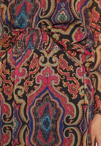 Robe à motifs multicolores sur fond noir, présentant des designs paisley complexes dans des teintes de rouge, bleu et or. Détail de taille élastique.