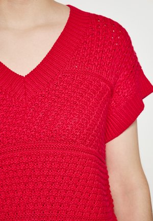 Red knitted top with a V-neck, short sleeves, and textured patterns. Features a combination of open and closed stitches for added detail.