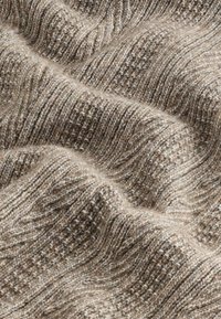 Textured brown knit fabric with a wavy pattern, featuring varying shades of beige and light brown. Soft, cozy appearance with visible stitches.