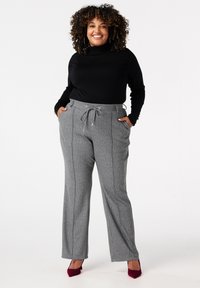 Grijze broek met een streepjespatroon, met een trekkoord in de taille, zijzakken en een relaxte pasvorm, gecombineerd met een zwarte coltrui.