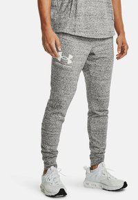 Šedé sportovní tepláky s texturovanou tkaninou, na levém stehně s bílým logem Under Armour a těsnými manžetami na kotnících.