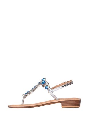 Sandalo piatto argento con tacco basso in legno e decorazioni con pietre preziose blu e trasparenti sulla cinghia sopra il piede.